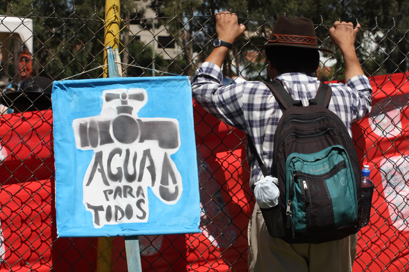 A protester holds a blue sign reading 'AGUA PARA TODOS' (Water for All) during the Cochabamba Water War demonstrations, symbolizing the demand for universal access to water.